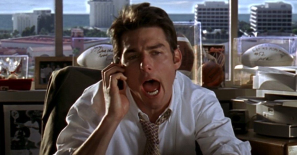 Tom Cruise as Jerry Maguire talking to his client showing enthusiasm. 