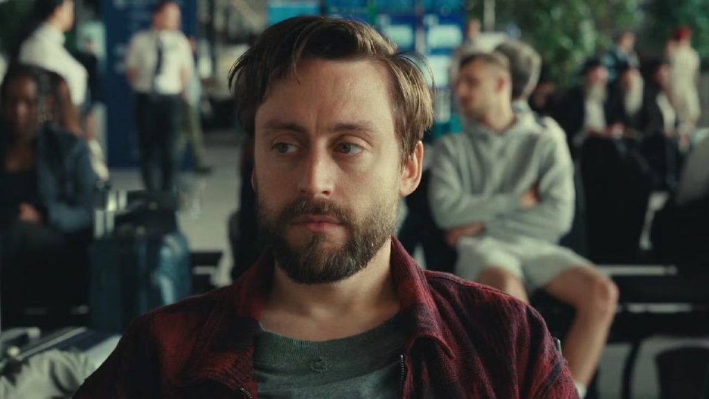 Kieran Culkin looking sideways while sitting in A Real Pain 