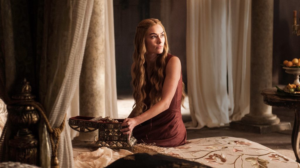 Cersei Lannister in a luxurious chamber sitting on a bed, wearing a simple red dress. She has her signature long blonde hair and is holding what appears to be an ornate wooden box.