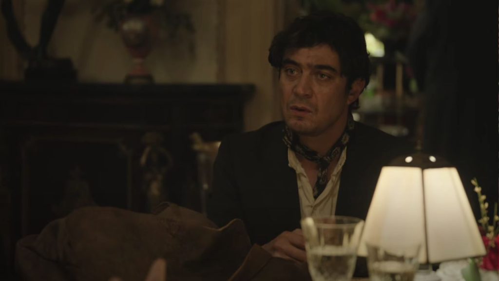 Riccardo Scamarcio sitting at a restaurant looking at someone in Modi: Three Days on the Wing of Madness