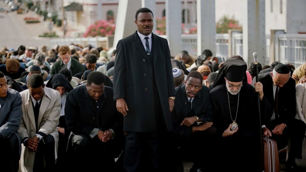 David Oyelowo as Martin Luther King Jr. in "Selma," standing tall among kneeling protesters in a powerful scene from the film.