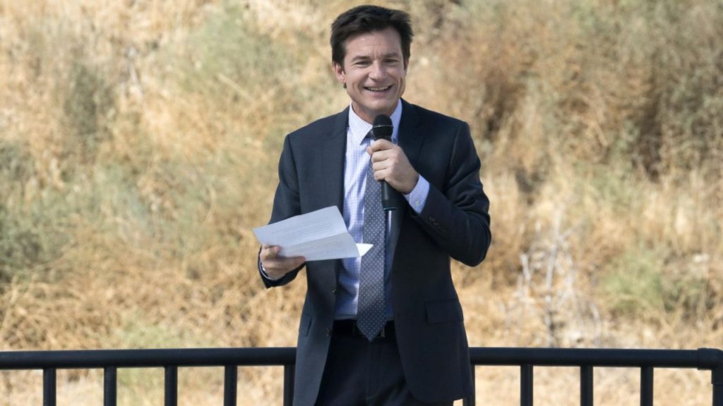 Jason Bateman holding a microphone and a paper in Arrested Development