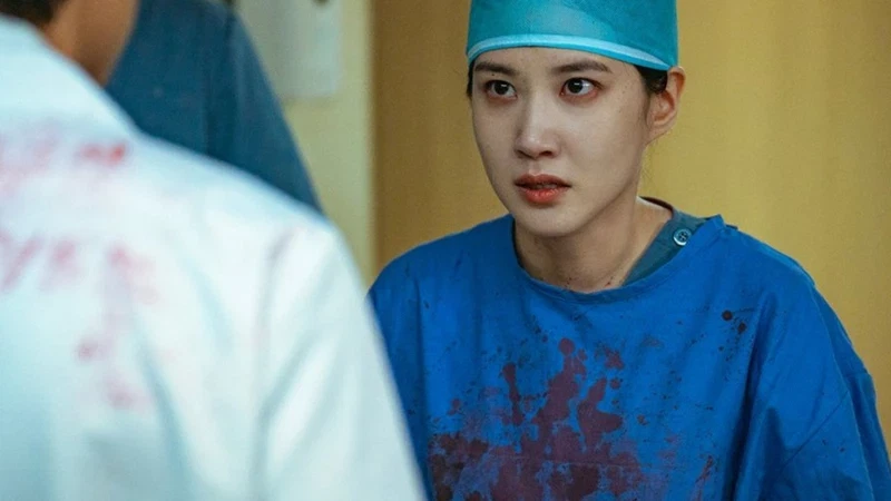 Park Eun-bin in "Hyper Knife" wearing blue scrubs and surgical cap with blood splattered on her clothing, looking concerned in a hospital setting.