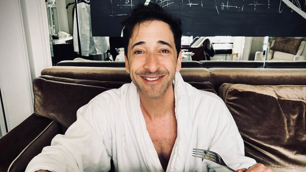 Adrien Brody eating his meal in a bathrobe