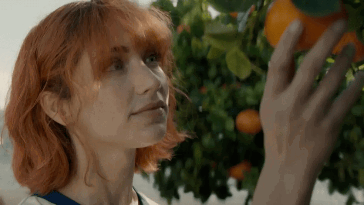 Emily Rudd as Nami looking at the tangerine tree in One Piece.