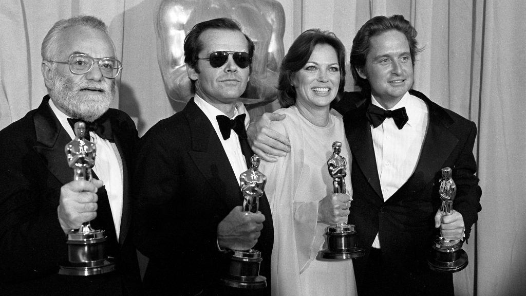 A historic black and white photograph showing Saul Zaentz, Jack Nicholson, Louise Fletcher, and Michael Douglas at an Academy Awards ceremony.