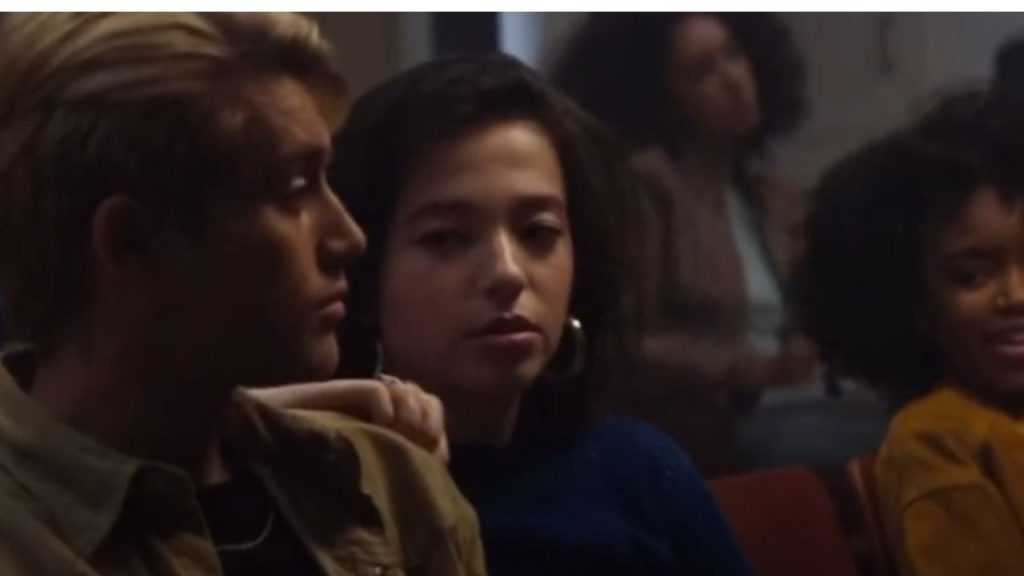 Mikey Madison in the center looking at a man beside her still from Monster