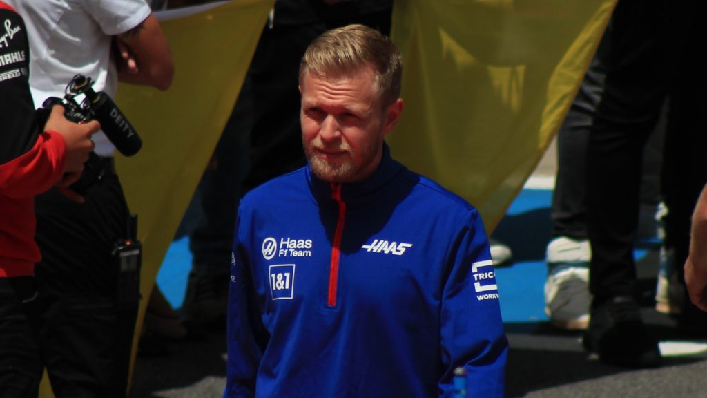 Kevin Magnussen in Haas F1 team blue jacket at what appears to be a team event or media appearance.