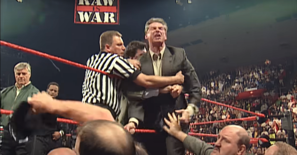 Mr McMahon held by the referee in the ring. 