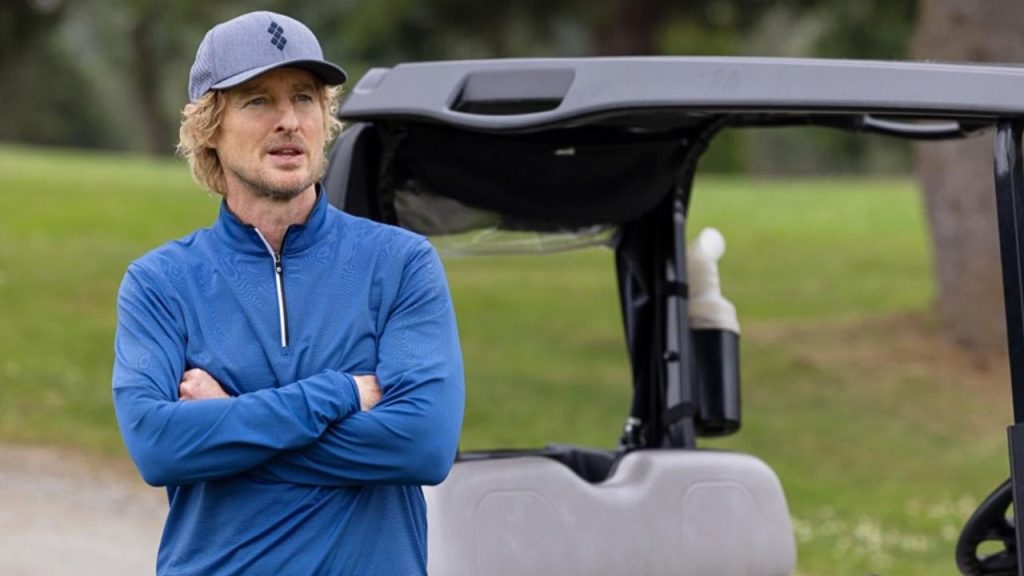 Owen Wilson standing beside a golf cart in Stick