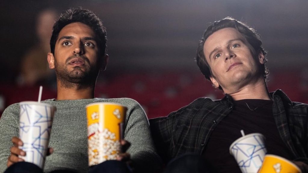 Karan Soni and Jonathan Groff in a movie theater in A Nice Indian Boy