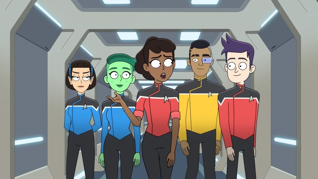 A scene from the animated series Star Trek: Lower Decks showing five diverse crew members in Starfleet uniforms standing in a corridor, including an alien crew member with green skin.