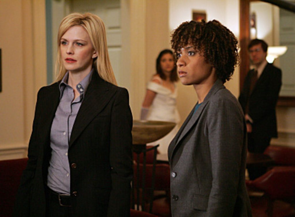 Kathryn Morris and Tracie Thoms looking at someone both wearing suits