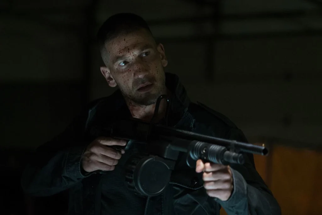 Jon Bernthal as Frank Castle carrying a gun in The Punisher.