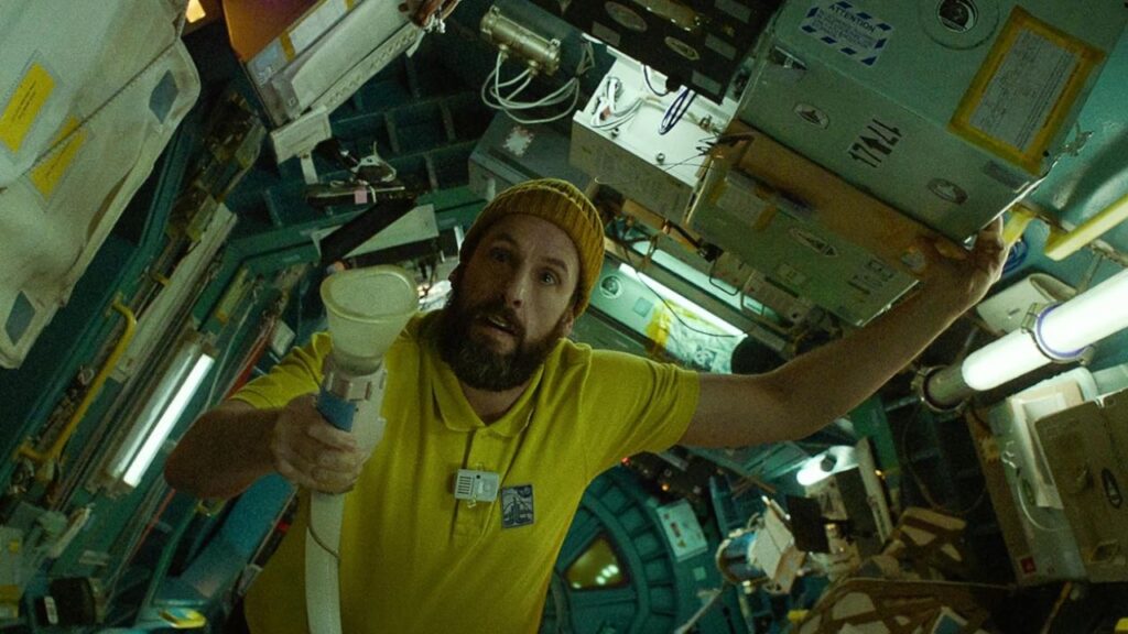 Adam Sandler holding a pipe in a space shuttle in Spaceman