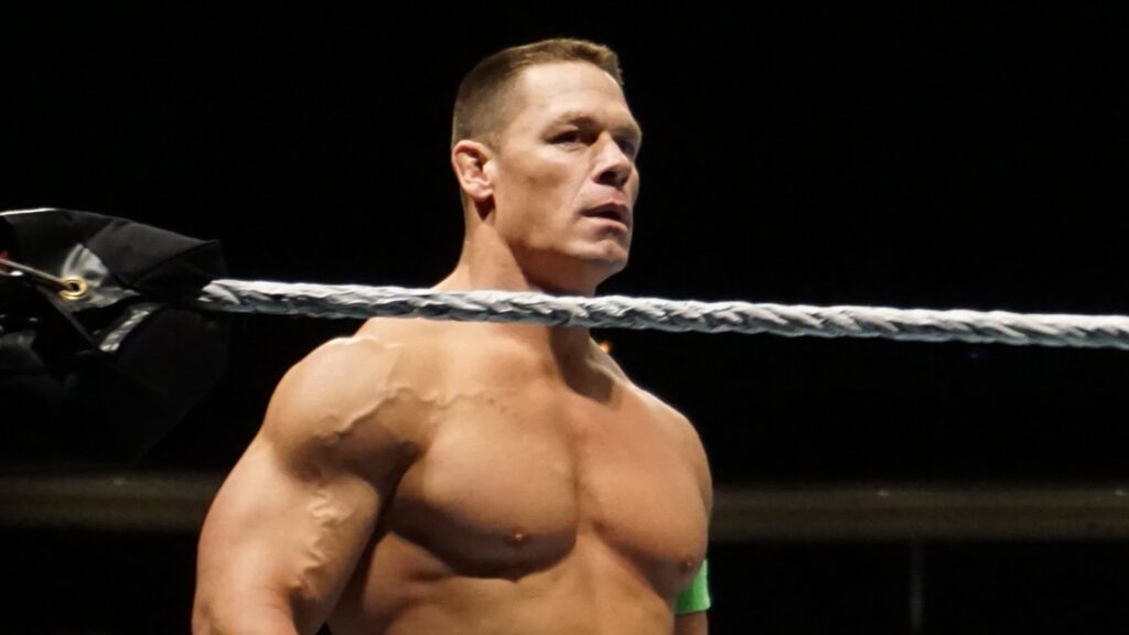 A close-up of John Cena with his signature short haircut and muscular physique in a WWE ring.