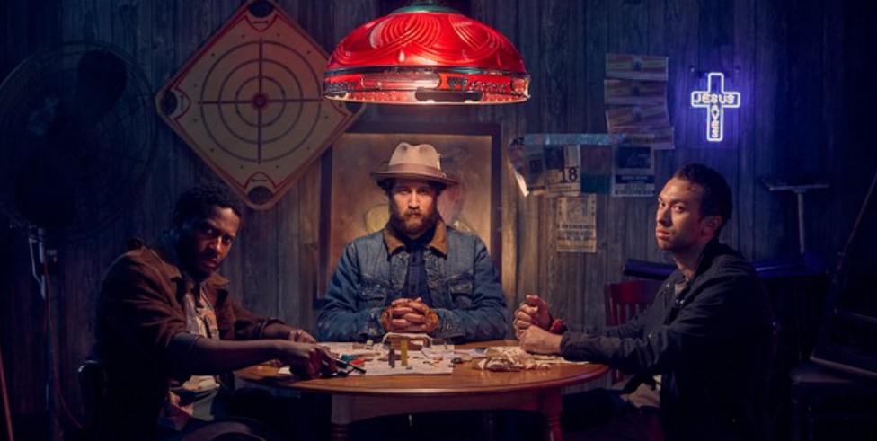 Brendan Bradley, Nican Robinson, and Jordon Bolden are sitting at a table, striking a serious and intense pose. 