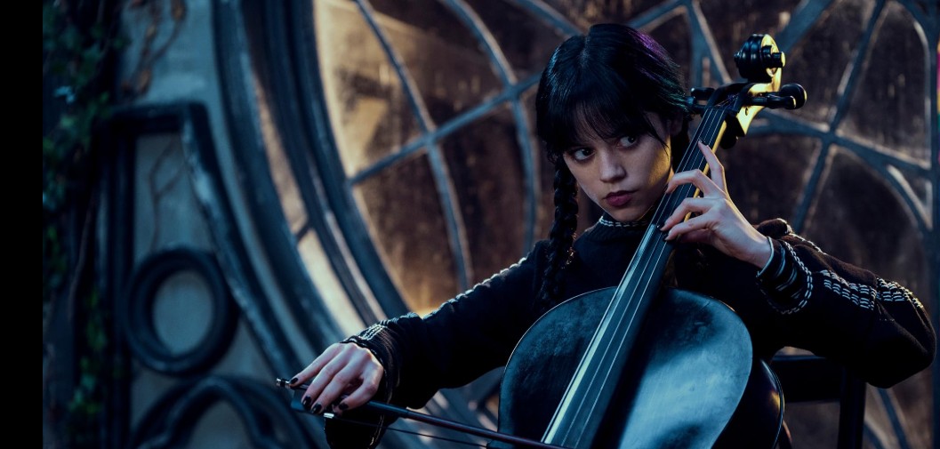 Jenna Ortega as Wednesday Addams playing an instrument, with a focused expression.