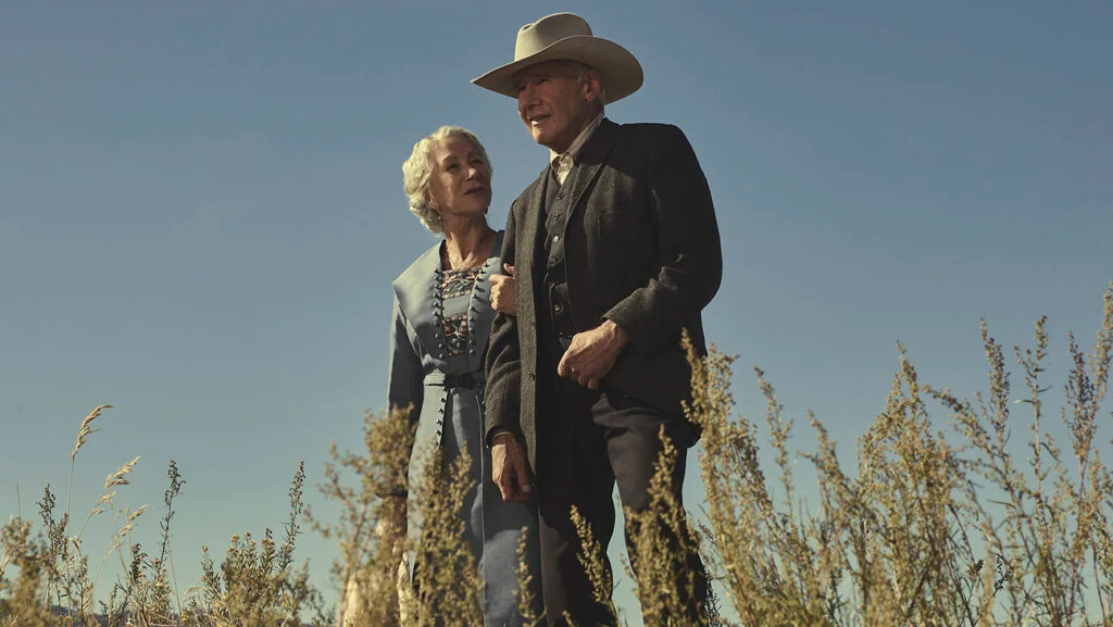 Harrison Ford and Helen Mirren walking hand-in-hand under the open sky in 1923.