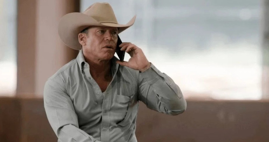 Taylor Sheridan playing the role of Travis Wheatley in Yellowstone wearing a cowboy hat and talking to someone on the phone.