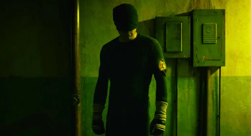 Matt Murdock's wearing his black suit in a dark hallway.