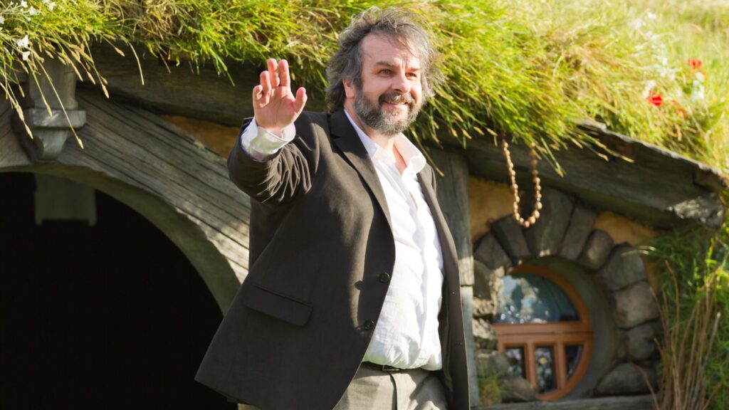10 Most Successful Non-American Directors in Hollywood 8 Sir Peter Jackson wearing a brown suit jacket and white shirt, waving at the camera. He's standing in front of a hobbit-hole at the world premiere of The Hobbit - An Unexpected Journey, held in Wellington, New Zealand.