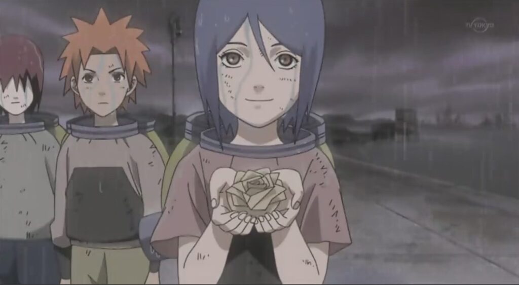 Konan holding a paper origami flower as she is accompanied by her fellow orphan friends Yahiko and Nagato. 