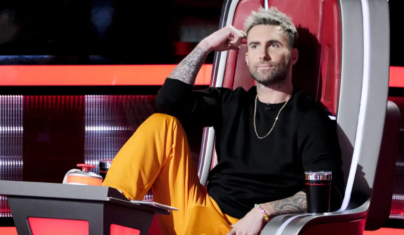 Adam Levine being is cool self sitting in the red judge's chair in The Voice.