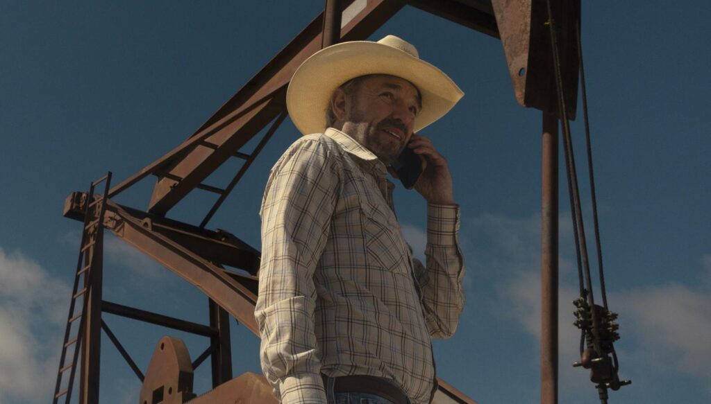 Taylor Sheridan’s ‘Landman’ Is More Similar to 97% Rated Legacy Show Than ‘Yellowstone’ 2 A character holding a phone to his ear while an oil rig works behind him in a still from Taylor Sheridan's Landman.