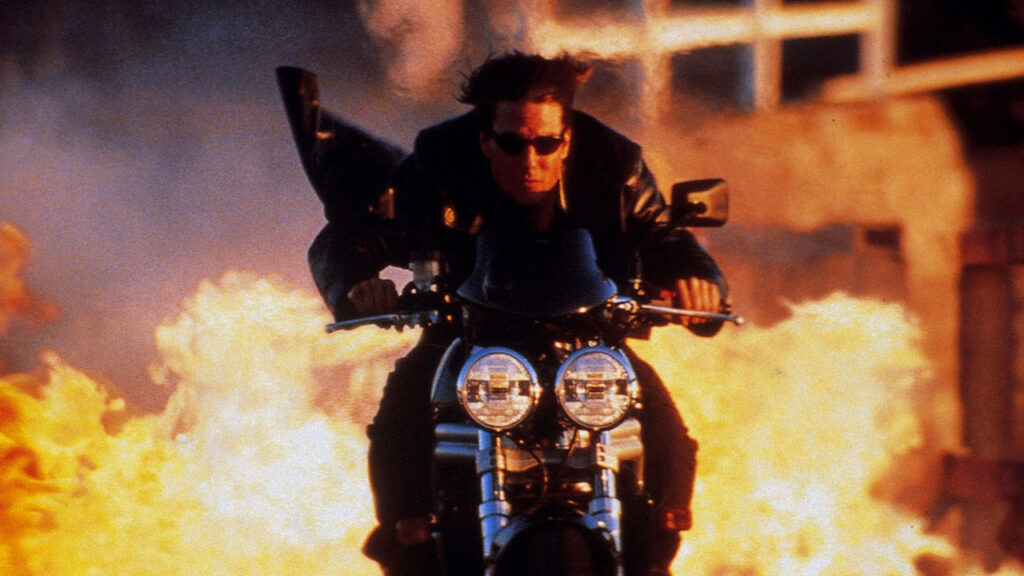 Tom Cruise drives motorcycle against the background of an explosion