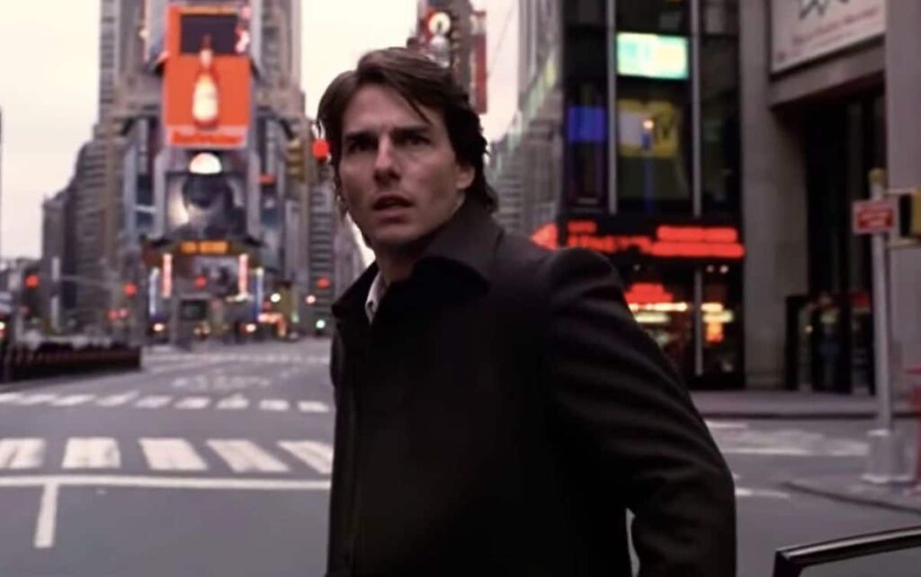 Tom Cruise looks around in the middle of the street with a shocked expression