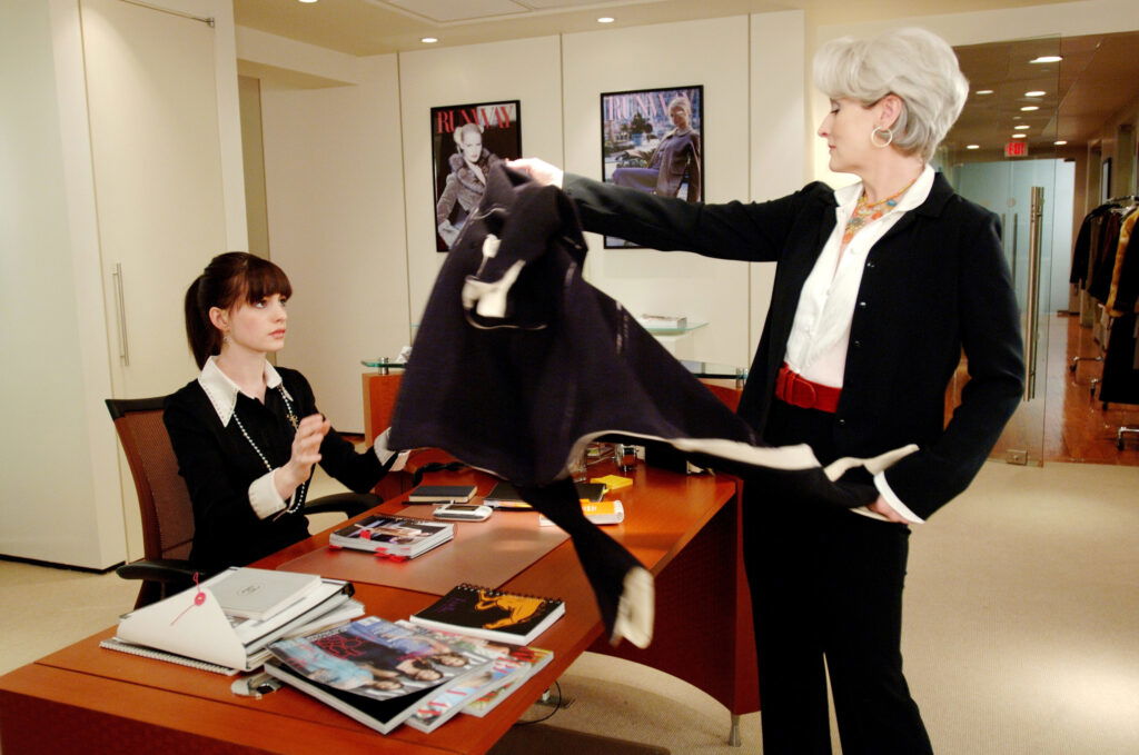 Imperious fashion magazine editor Miranda Priestly (Meryl Streep) dumps her coat on the desk of new assistant Andy Sachs (Anne Hathaway). 