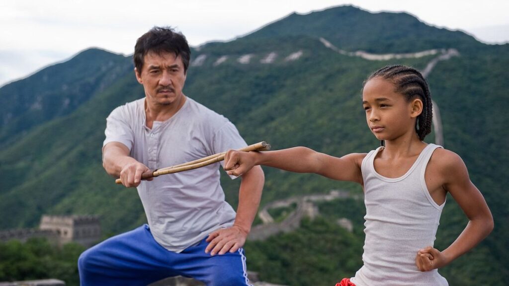 The Shadow's Edge Looks Like Police Story 4 But Jackie Chan Is Not Trying to Make You Laugh in His Next Movie 2 Jackie Chan with a stick in his hand placed on Jaden Smith's extended hand in his training scene from The Karate Kid.