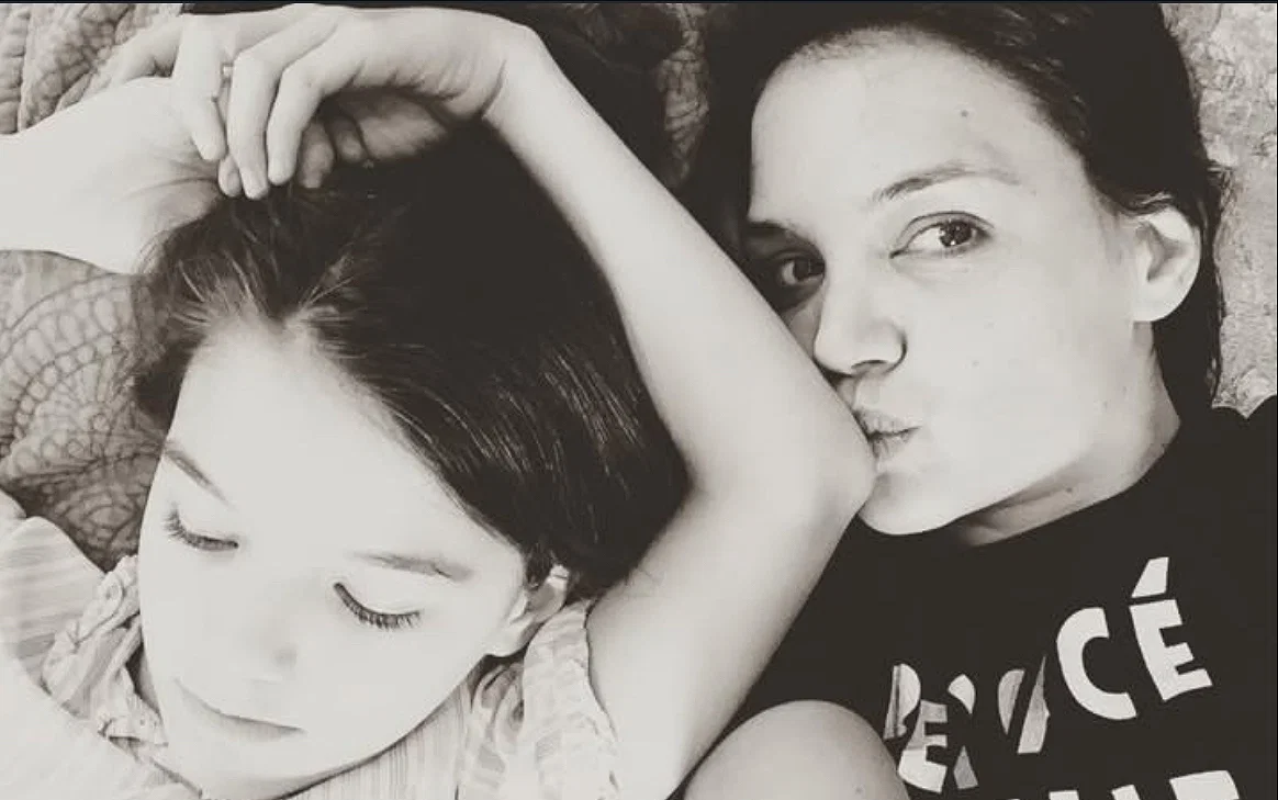 Suri Cruise lying beside her mother Katie Holmes