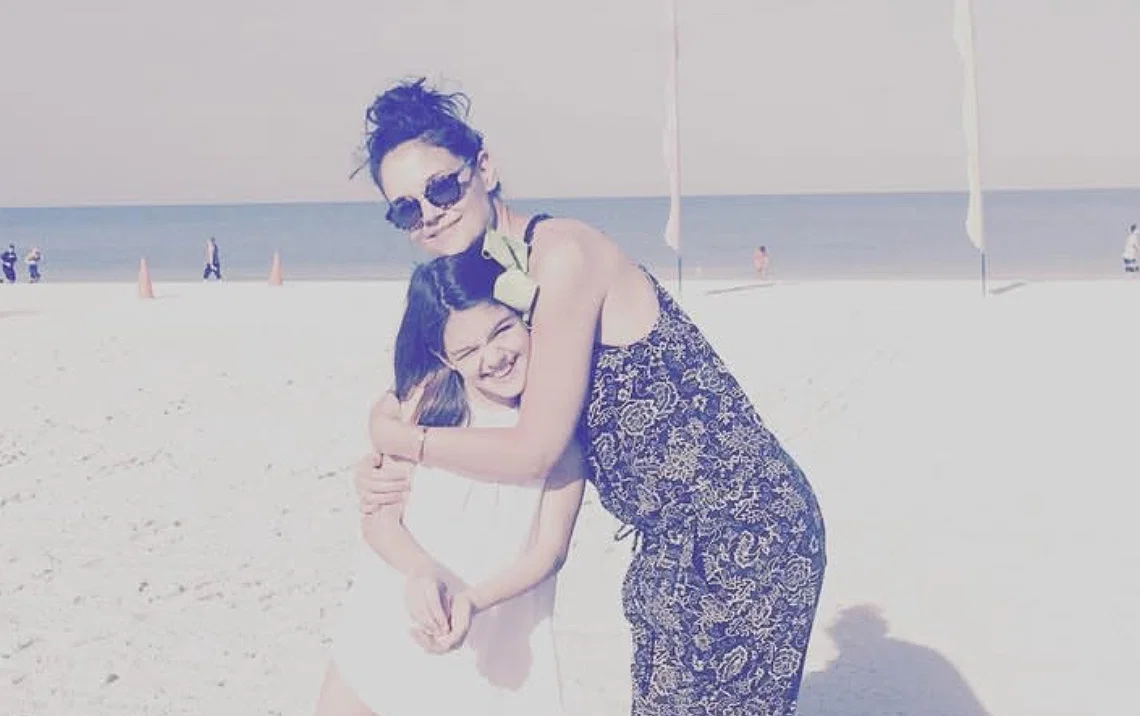 Suri Cruise as a child standing on the beach with her mom Katie Holmes