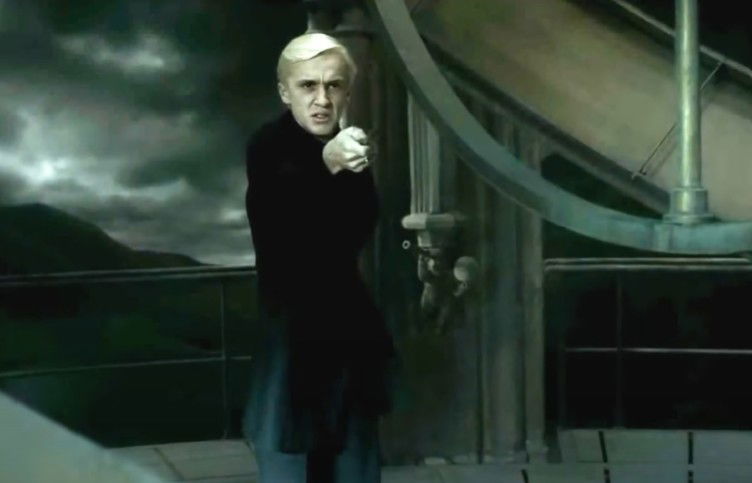 Draco Malfoy pointi g his wand at Dumbledore in the astronomy tower.