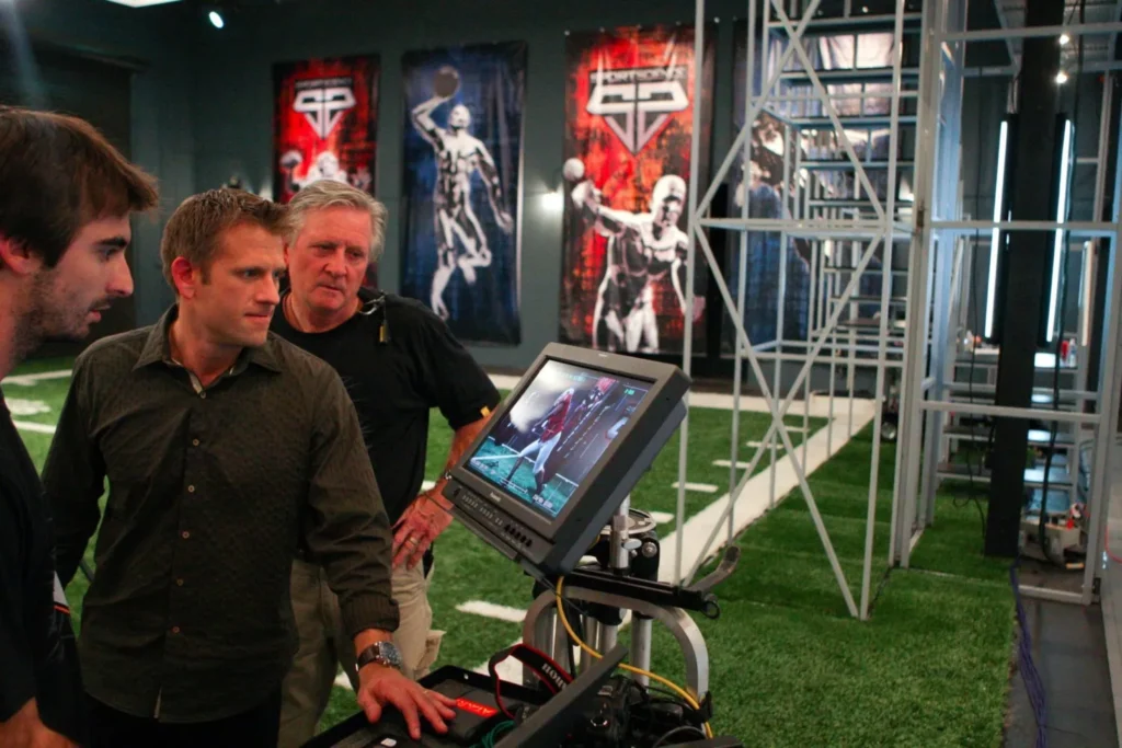 How Did John Brenkus Die? Sport Science Host’s Cause of Death Revealed 1 John Brenkus standing and looking at a monitor in Sport Science.