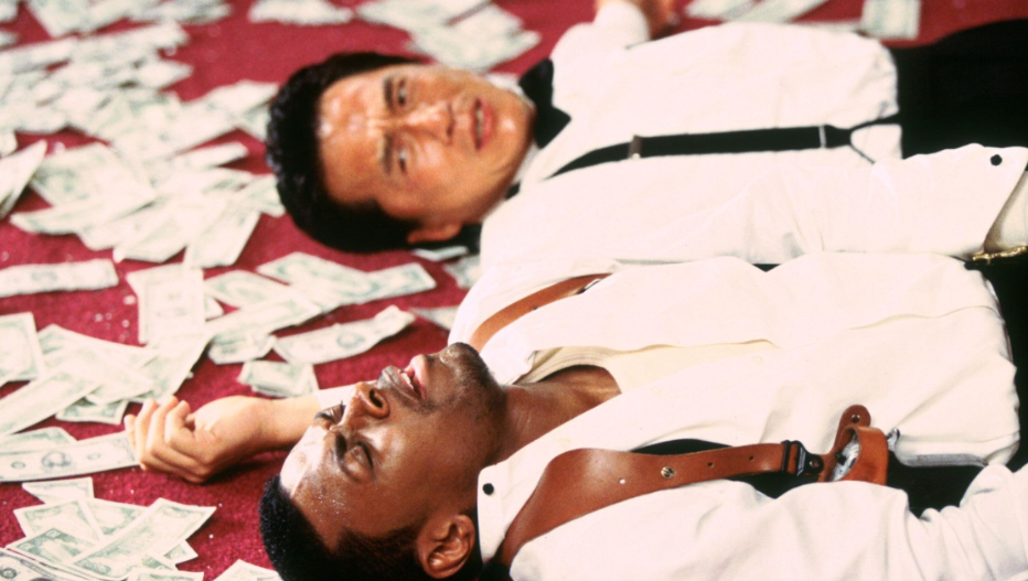 Lee and Carter are lying on the floor, exhausted. Lee is looking at Carter, whose eyes are closed. The floor is covered with money.