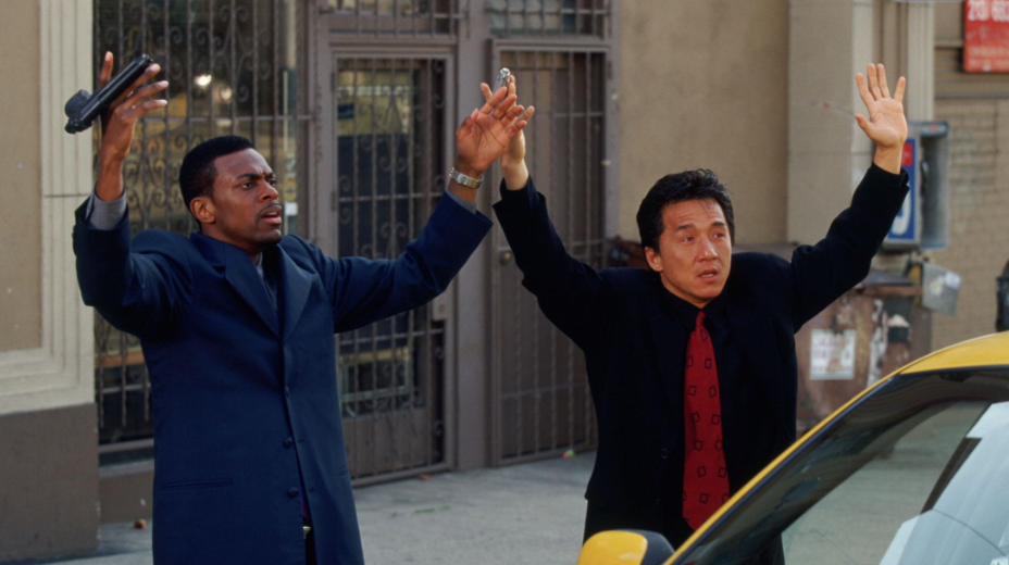 Lee and Carter are standing beside a taxi with their hands raised in surrender.