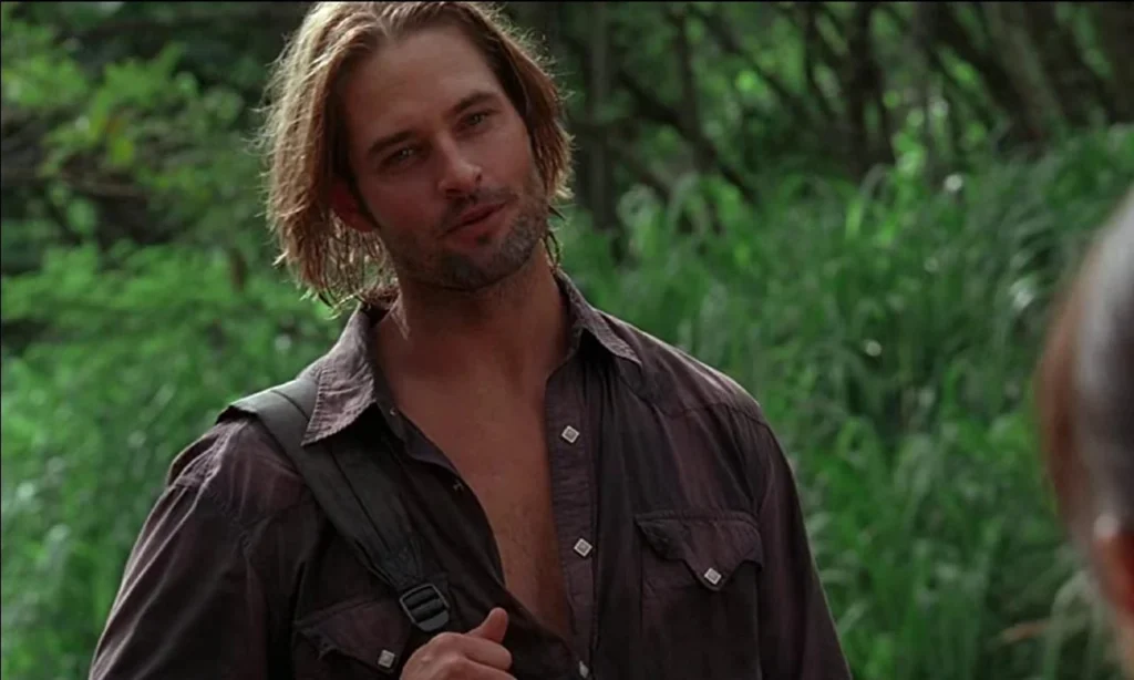 Josh Holloway smiles while having a conversation in the woods