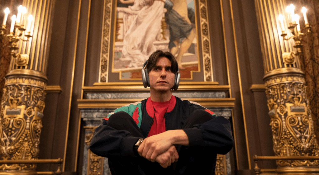 Real Reason ‘Étoile’ on Prime Video Will Not Return for Season 2: Explained 9 Tobias Bell is sitting in a grand, golden room, wearing big headphones and a stylish jacket. He looks serious, like he's deep in thought
