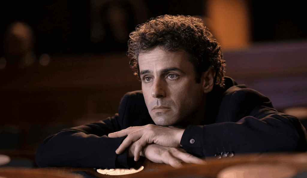 Real Reason ‘Étoile’ on Prime Video Will Not Return for Season 2: Explained 10 Jack McMillan rests his arms on a chair in a dark theatre, looking sad and lost in thought.