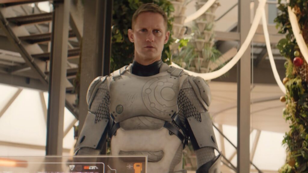 20 Absolutely Best TV Shows to Watch Right Now (June 2025) 63 Murderbot without his helmet stands in a high-tech facility with glass panels and advanced equipment surrounding him.