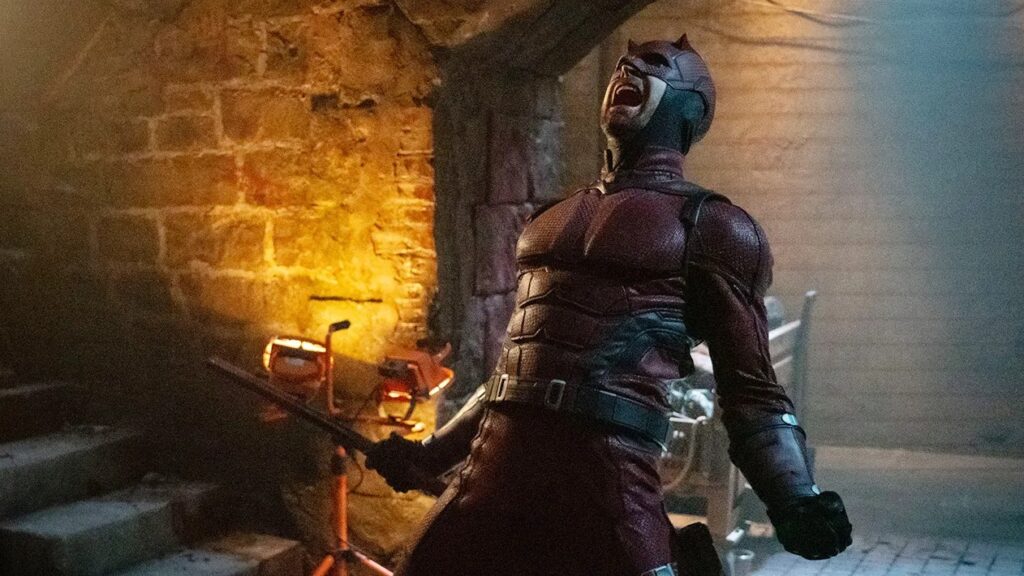 20 Absolutely Best TV Shows to Watch Right Now (June 2025) 66 Charlie Cox as Daredevil screams while facing upwards in what appears to be an underground tunnel or basement with brick walls.