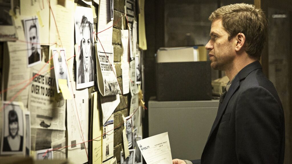 20 Absolutely Best TV Shows to Watch Right Now (June 2025) 79 DCI James Hardy (Jamie Sives) in a dark shirt examines a wall covered with photographs, documents, and investigation materials connected by red string.