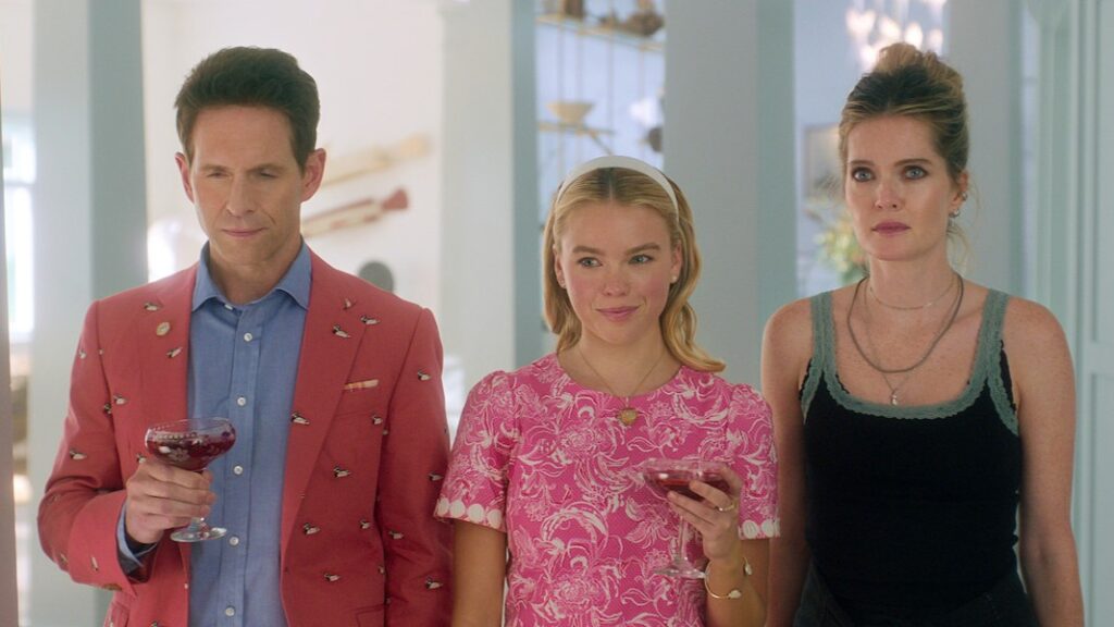 20 Absolutely Best TV Shows to Watch Right Now (June 2025) 84 Ethan Corbin III (Glenn Howerton), Simone, and Devon stand together in an elegant interior - Ethan in a coral blazer with small patterns holding a drink, Simone in a pink patterned dress also holding a drink, and Devon in a dark sleeveless top.