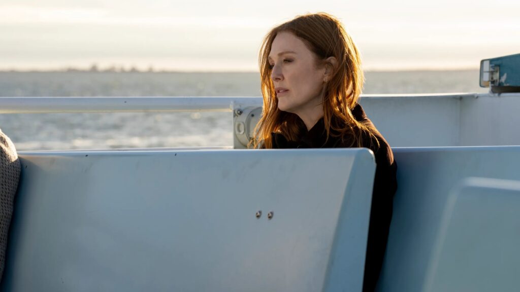 20 Absolutely Best TV Shows to Watch Right Now (June 2025) 85 Michaela wearing a dark jacket sits on a boat, looking pensively to the side with ocean and horizon visible in the background.