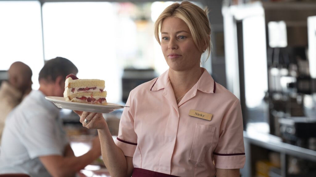 20 Absolutely Best TV Shows to Watch Right Now (June 2025) 99 Nicky Macintosh (Elizabeth Banks) in a pink waitress uniform with a name tag reading "Nicky" holds a plate with a slice of layered cake in a diner.