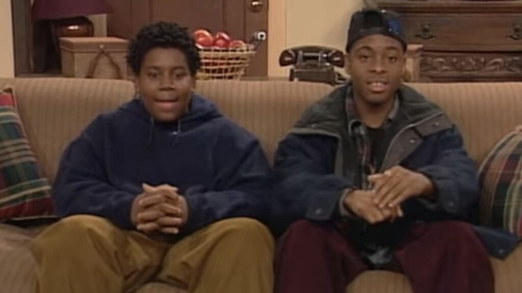 10 Insanely Popular TV Shows From the ‘90s You Can Stream on Netflix 7 Kenan Thompson and Kel Mitchell sitting on a couch in casual winter clothing - hoodies and jackets - in what appears to be a living room setting from their sitcom.