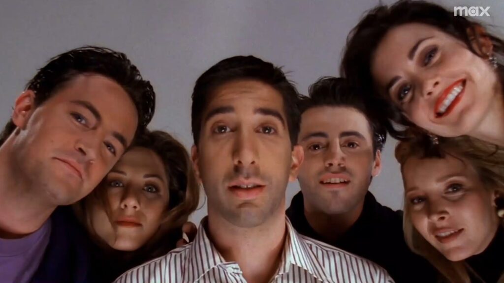 10 Insanely Popular TV Shows From the ‘90s You Can Stream on Netflix 20 A still from Friends showing all six cast members in a close group huddle looking down at the camera.